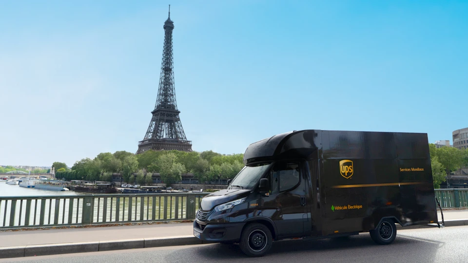 an electric U P S truck drives by the eiffel tower