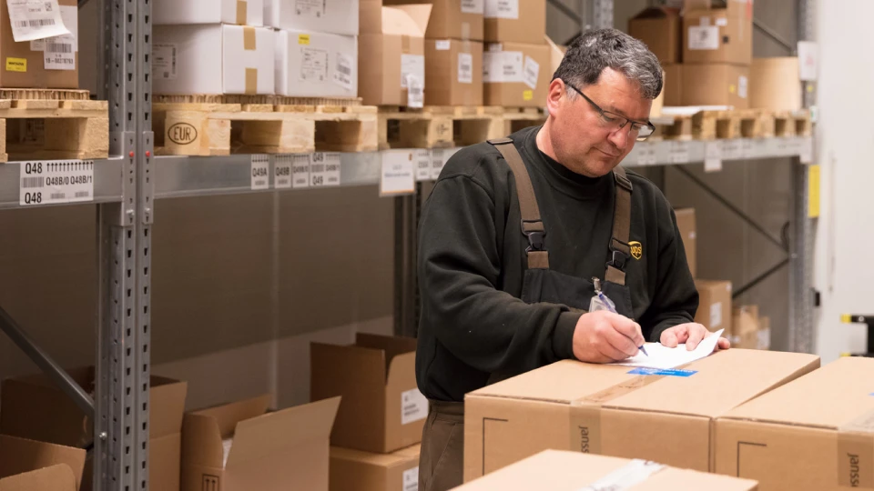 a man in a warehouse writing a note on a box