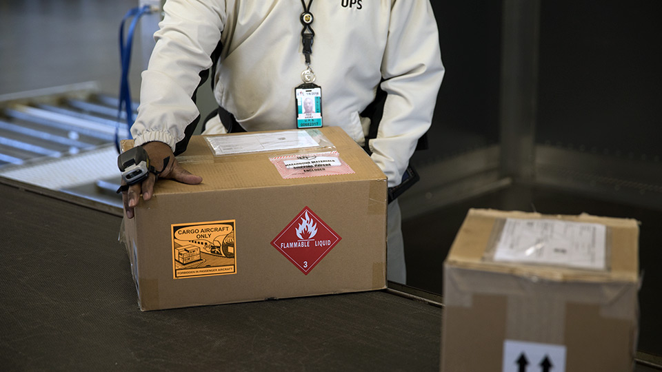 Person in lab coat packing a box