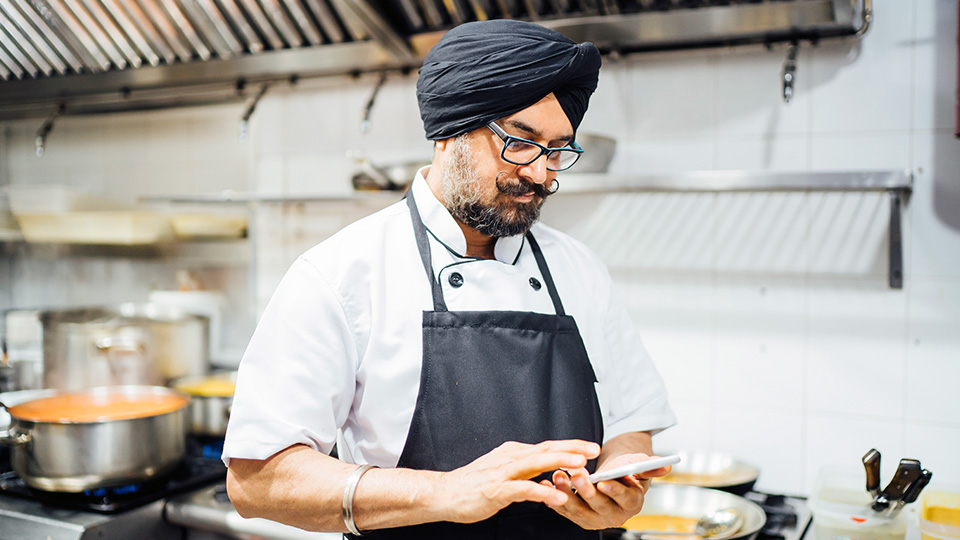 Cook in kitchen looking at phone