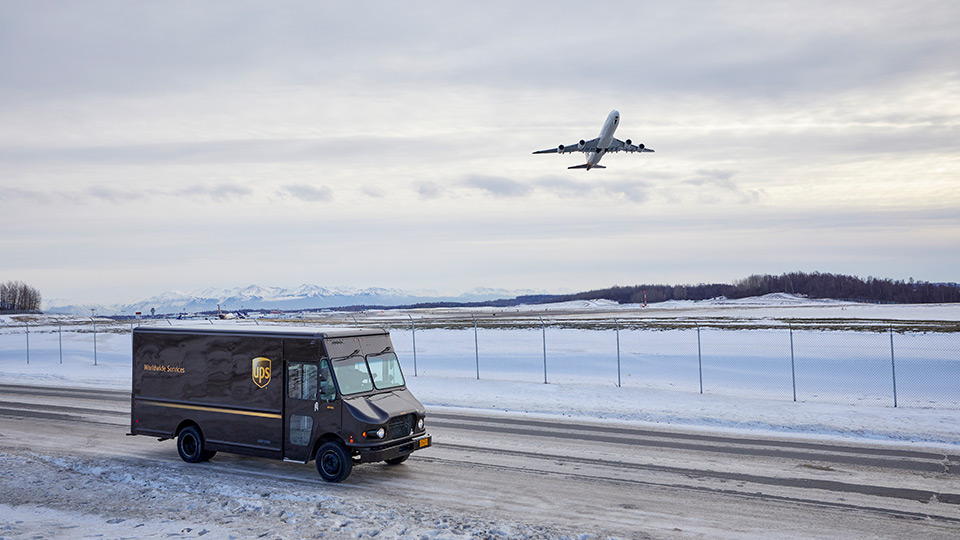 UPS truck with plane flying above it