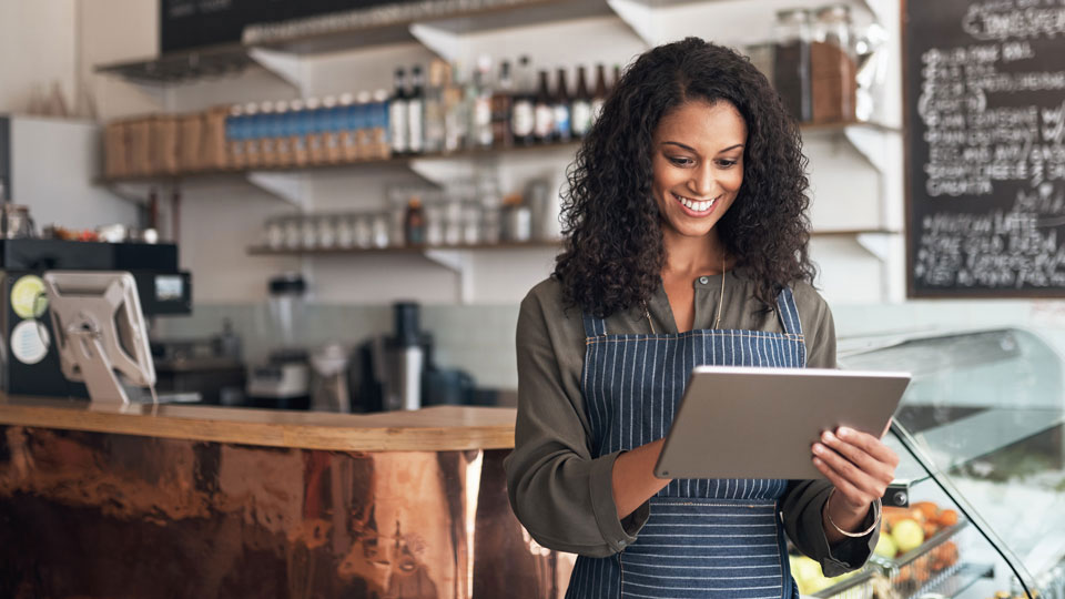 Smiling woman working in restaurant, on tablet.