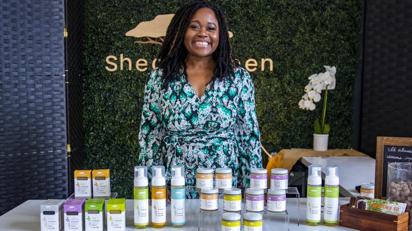 A person smiling and standing behind a table