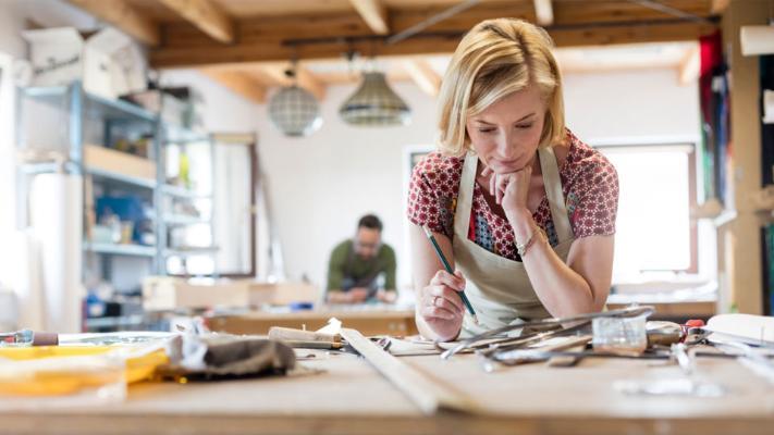 A young woman and small business owner working on a product design in her workshop