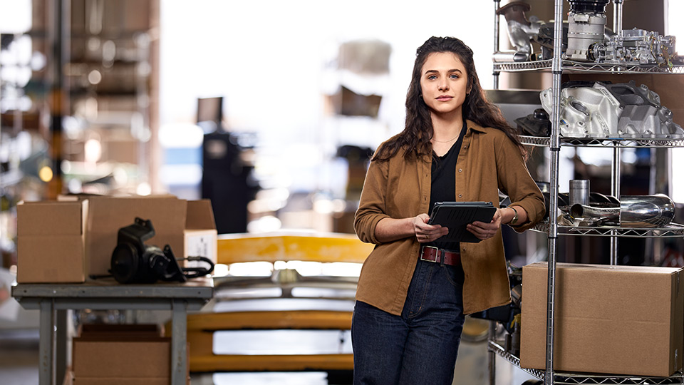 Woman leaning against a shelf holding a tablet