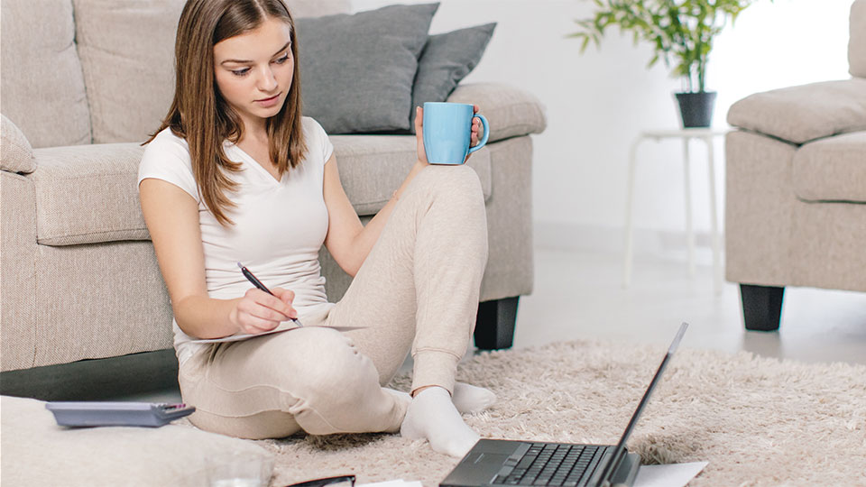 Kvinde sidder med en bærbar computer og papir