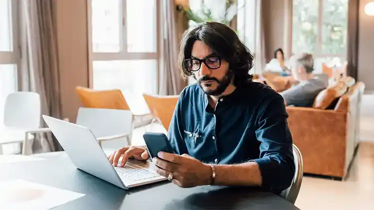 Man checking both laptop and mobile device.