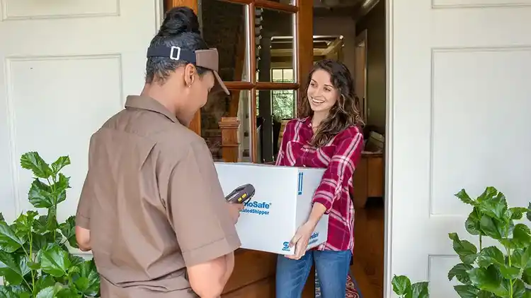 Woman handing driver parcel at door