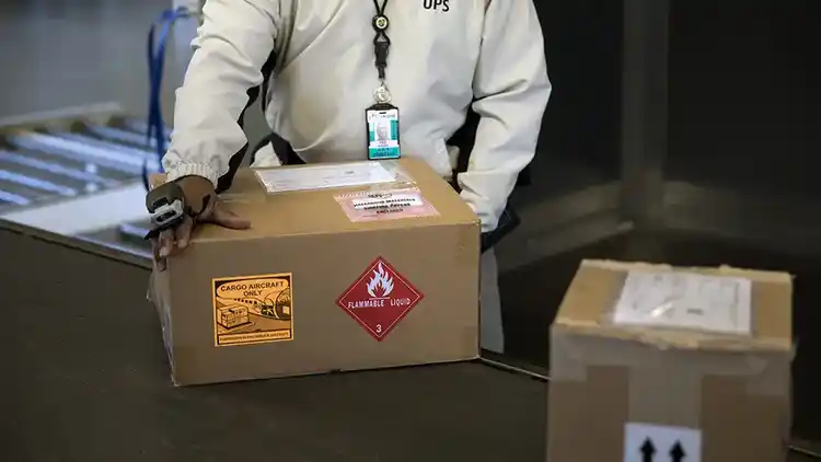 Person in lab coat packing a box